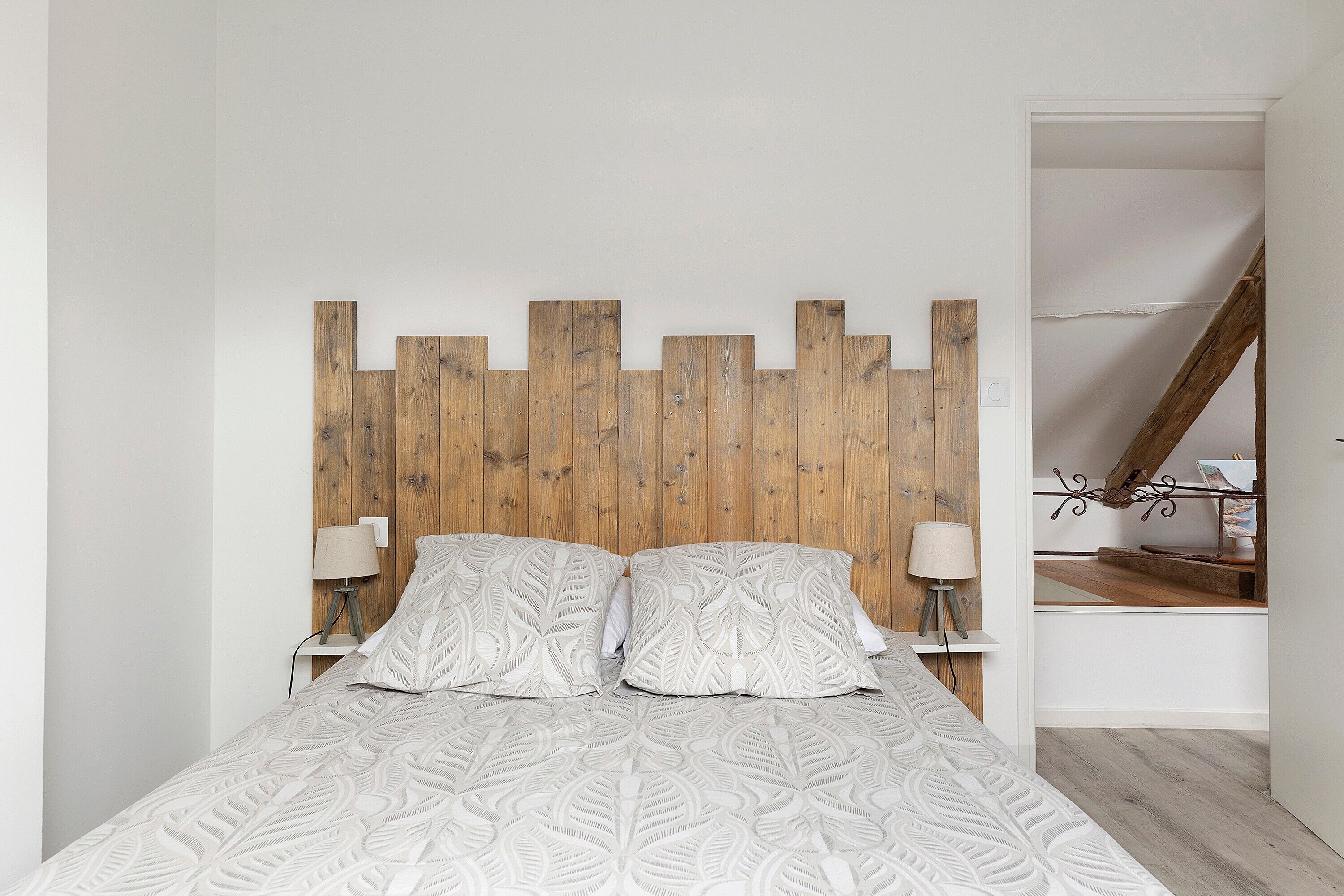 Une chambre à coucher avec une tête de lit en bois, deux tables de chevet avec des lampes et une couvre-lit à motifs.
