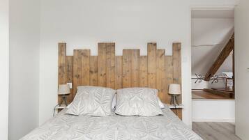 Une chambre à coucher avec une tête de lit en bois, deux tables de chevet avec des lampes et une couvre-lit à motifs.