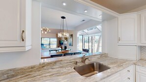 Una cucina moderna con un'isola grande, lavello in acciaio inossidabile e illuminazione a sospensione.