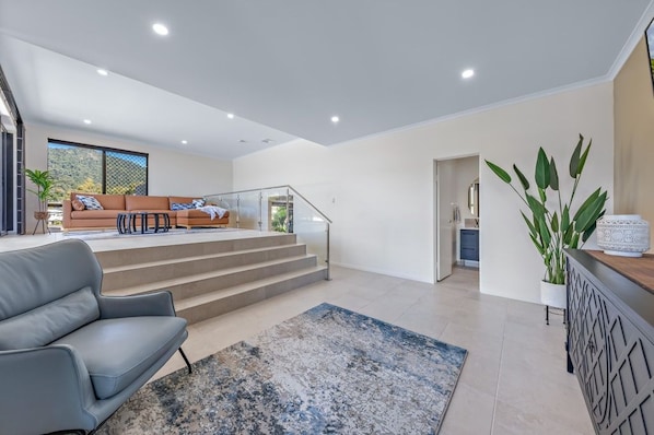 A modern living room with a sofa, a coffee table, and a staircase leading to an upper level. - Island Vista Penthouse (Airlie Beach)