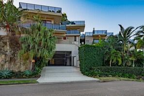 A multi-story residential building with a gated entrance, surrounded by lush greenery and palm trees. - Island Vista Penthouse (Airlie Beach)