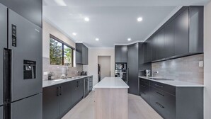 A modern kitchen with dark cabinetry, a central island, and built-in appliances.