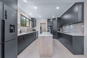 A modern kitchen with dark cabinetry, a central island, and built-in appliances.
