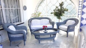 Ein Zimmer mit Korbmöbeln, einem runden Tisch und einem großen Fenster mit Blick.
