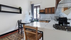 A kitchen with a dining table, chairs, a coffee machine, and a built-in oven.