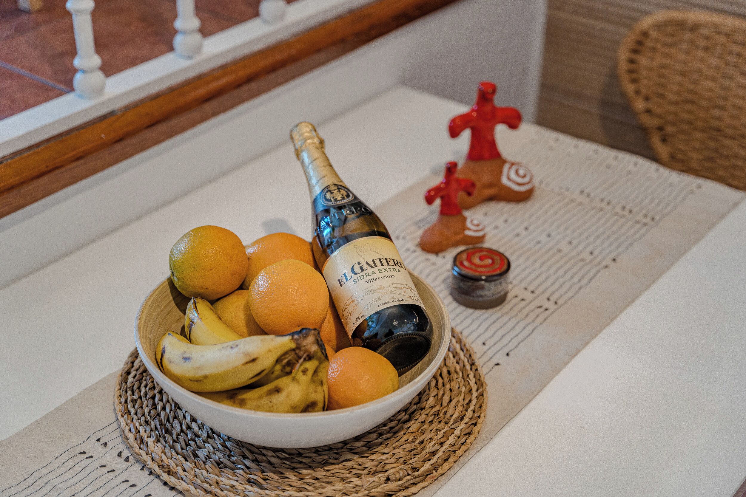 A bowl of fruit and a bottle of champagne on a table.