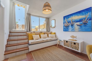 A staircase leading to a balcony with a view of the sea, a painting of boats on the wall, and a white console table with decorative items. - Arche Noa Apartment with sea view (Los Gigantes)