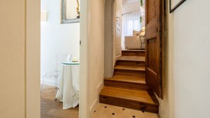 A staircase leading to a room with a white door, a small table with a glass top, and a chair. - Tornabuoni Cozy Apartment (Firenze)