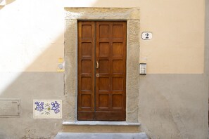 A double wooden door with a number '2' above it, set in a beige wall with a small window below. - Tornabuoni Cozy Apartment (Firenze)