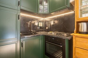A kitchen with green cabinets, a gas stove, an oven, and a sink. - Tornabuoni Cozy Apartment (Firenze)