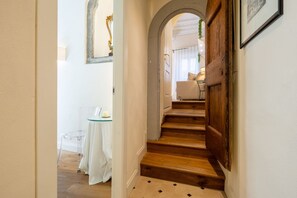 A staircase leading to a room with a white door, a small table with a glass top, and a chair. - Tornabuoni Cozy Apartment (Firenze)