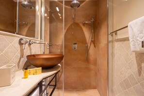 A modern bathroom with a large copper sink, a glass shower enclosure, and a towel rack. - Tornabuoni Cozy Apartment (Firenze)