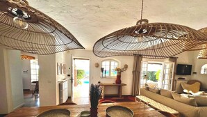 A spacious living room with a wooden dining table, two large woven ceiling lamps, a sofa, and a television. - Villa with sea and Esterel views: 5 bedrooms, swimming pool, air conditioning. (Saint-Raphaël)