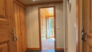 Un couloir avec des portes en bois, un tapis rouge et une vue sur une pièce dont le plafond est également en bois.