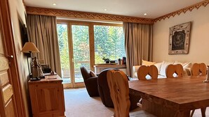 Un espace repas comprenant une table et des chaises en bois, un canapé et une vue sur l’extérieur.