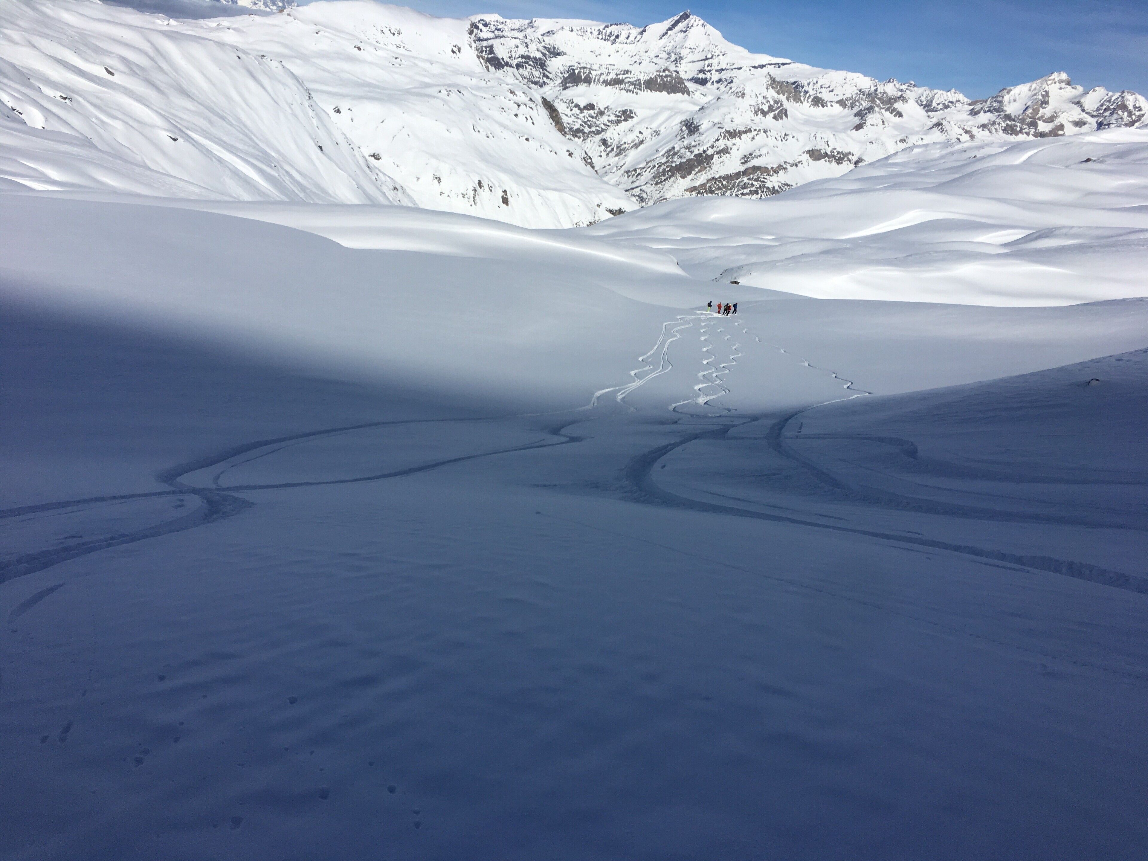 A snow-covered landscape with a group of people in the distance.