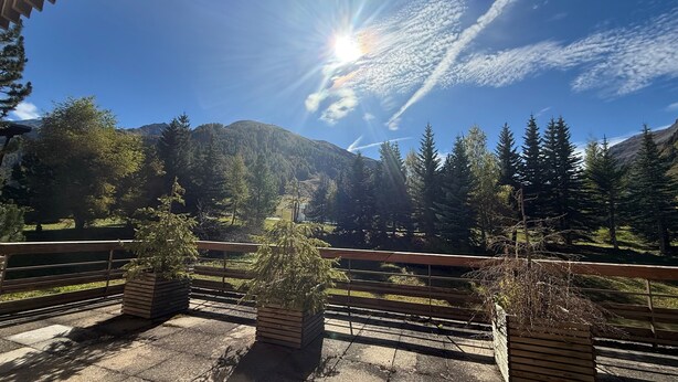 Une terrasse en bois avec des bancs, offrant une vue sur un paysage montagneux.