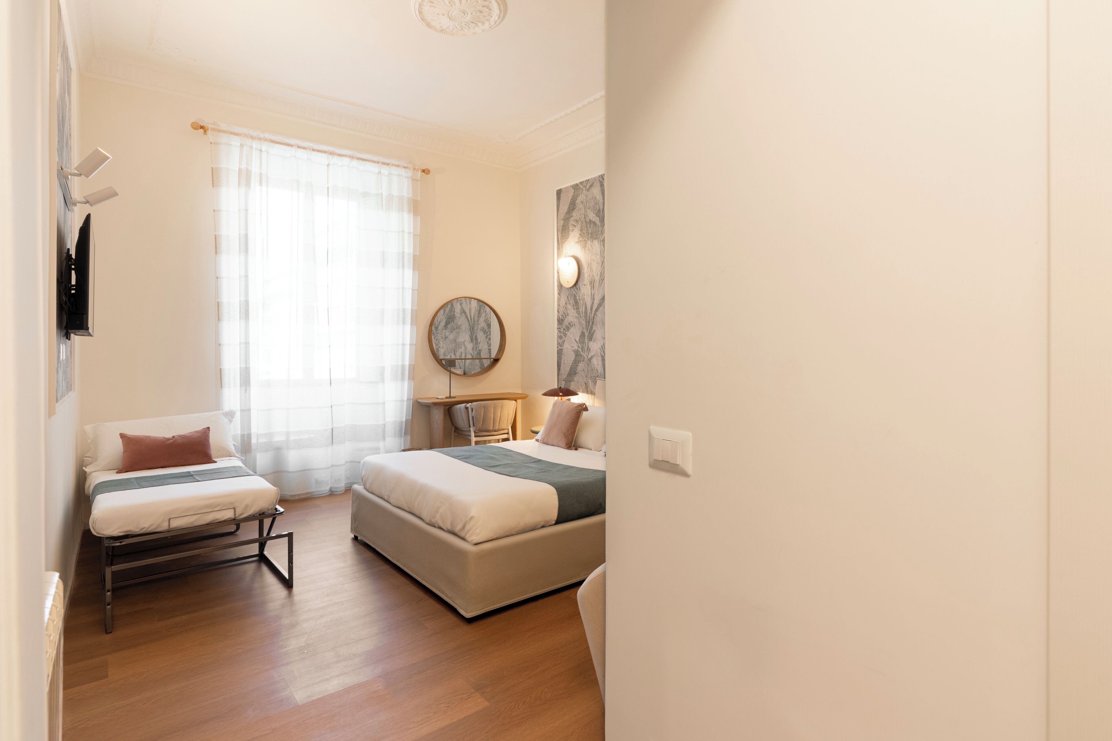 A bedroom with a bed, a chair, a table, and a mirror.