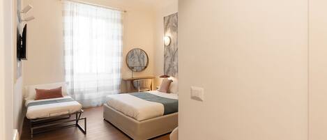 A bedroom with a bed, a chair, a table, and a mirror.