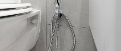 A modern bathroom with a toilet, a shower head, and a towel rack.