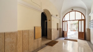 A hallway with a tiled floor, a wooden door, and a large arched doorway. - ReRent Rooms - 81 MANZONI GUESTHOUSE (Rome)