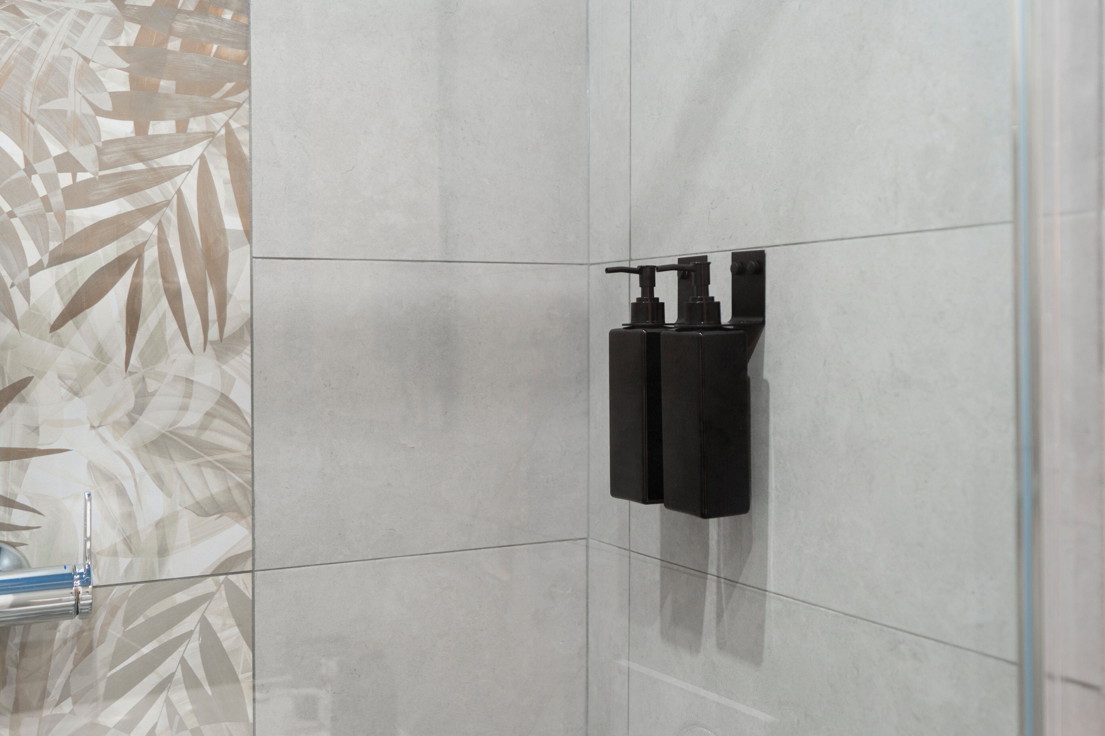 Un baño de diseño moderno, con un espejo grande, un dispensador de toallas negro y un revestimiento de pared estampado.