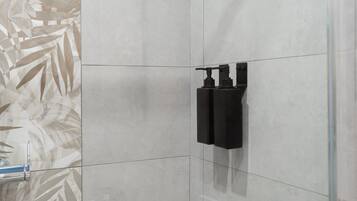 Un baño de diseño moderno, con un espejo grande, un dispensador de toallas negro y un revestimiento de pared estampado.