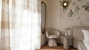 A room with a bed, a chair, a small table, a mirror, and a wall with a leaf pattern. - ReRent Rooms - 81 MANZONI GUESTHOUSE (Rome)