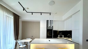 Une cuisine moderne dotée d’un îlot central, de tabourets de bar et d’un coin repas avec une table et des chaises blanches.