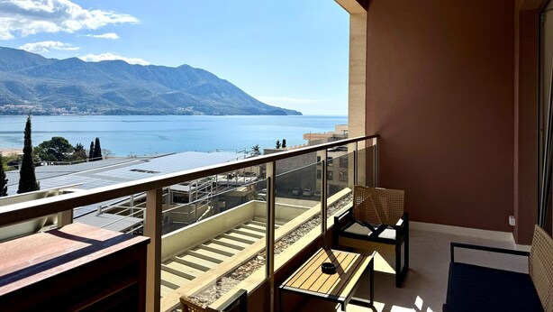 Un balcon avec vue sur un lac et des montagnes, aménagé avec une table et des chaises.