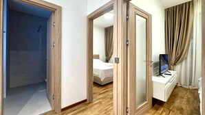 Une chambre d’hôtel équipée d’une douche, d’un lit, d’un bureau avec un ordinateur et d’un miroir.
