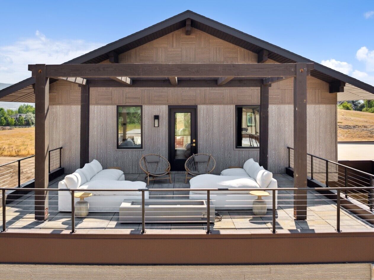 A modern building with a covered outdoor seating area featuring white sofas and wicker chairs.