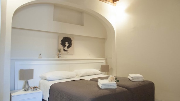 Un dormitorio con cama, mesitas de noche, lámpara y un adorno en la pared.