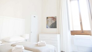 Habitación de hotel con cama, mesita de noche, cortinas y un cuadro en la pared.
