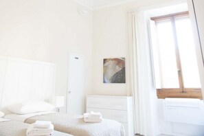 A hotel room with a bed, a bedside table, a nightstand, a window with curtains, and a painting on the wall. - Tornabuoni Classic Apartment  (Firenze)