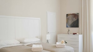 Una habitación de hotel con cama, mesita de noche, cómoda y un cuadro en la pared.