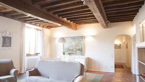 A living room with a sofa, a dining table, and chairs. There is a painting on the wall and a window with curtains. - Tornabuoni Classic Apartment  (Firenze)