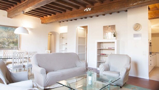 A spacious living room with a high wooden ceiling, white sofas, a glass coffee table, and built-in shelving. - Tornabuoni Classic Apartment  (Firenze)