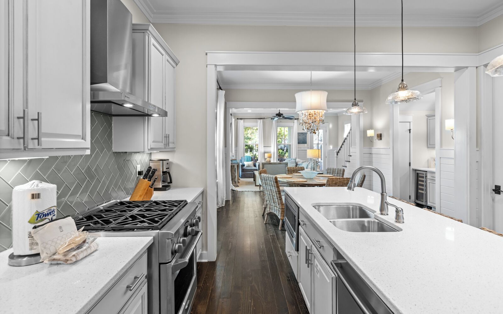 A modern kitchen with white cabinetry, a gas stove, and a large island with a sink.
