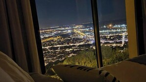 A view from a window overlooking a cityscape at night, with buildings and lights visible. - Le Rouquier Studio with exceptional view terrace (Sète)