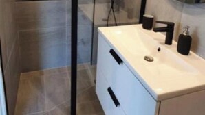 A modern bathroom with a shower, a sink with a mirror, and a white cabinet. - Le Rouquier Studio with exceptional view terrace (Sète)