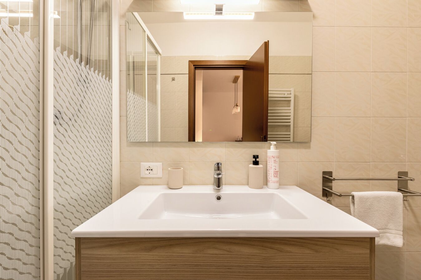 A modern bathroom with a large sink, mirror, and towel rack.