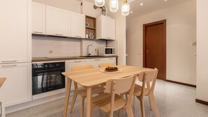 Eine moderne Küche mit weißen Schränken, einem Holztisch und Pendelleuchten.