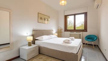 Une chambre à coucher avec un lit, des tables de chevet, une lampe, une fenêtre et une chaise.