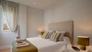 A neatly made bed with pillows and a blanket, bedside lamps, and a window with curtains. - Salmosalar Apartment in Cangas de Onís (Cangas de Onís)