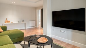 A modern living room with a flat-screen TV, green sofa, and a small table with a bowl and remote. - Salmosalar Apartment in Cangas de Onís (Cangas de Onís)