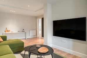 A modern living room with a flat-screen TV, green sofa, and a small table with a bowl and remote. - Salmosalar Apartment in Cangas de Onís (Cangas de Onís)
