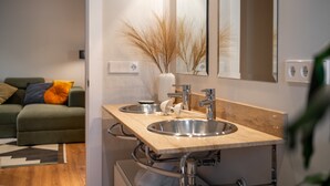 A modern bathroom with two sinks, a mirror, and a vase with dried plants. - Salmosalar Apartment in Cangas de Onís (Cangas de Onís)