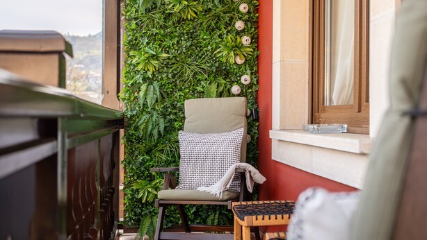 A balcony with a chair, a small table, and a vertical garden wall. - Salmosalar Apartment in Cangas de Onís (Cangas de Onís)