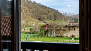 A view from a window of a rural landscape with a mountain in the distance, a red house, and a lamp post. - Salmosalar Apartment in Cangas de Onís (Cangas de Onís)